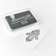 Tsukineko Stempelkissen und ein weißer Geschenkanhänger zeigen ein verziertes schwarzes Stempelmuster, das eine satinierte samtige Ausstrahlung auf weißem Hintergrund erzeugt.