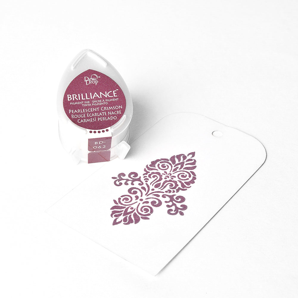 Tsukineko Red Brilliance Stempelkissen mit hochpigmentierter Tinte sitzt neben einem weißen Papieranhänger, der mit einem zarten floralen Muster bestempelt ist.