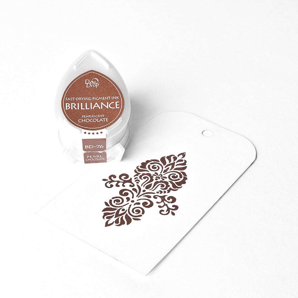 Tsukineko Brown Brilliance Stempelkissen und ein weißes Etikett mit einem aufwendigen braunen Blumenmuster in der Mitte geprägt, Hervorhebung seiner hochpigmentierte Tinte für knackige, detaillierte Eindrücke.