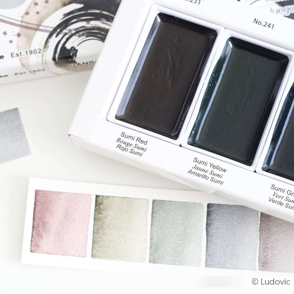 Nahaufnahme eines Aquarellfarbensets und Farbmuster mit Kuretake Aquarellfarbe in Sumi-Rot, -Gelb und -Grün aus der Gansai Tambi Sumi Colors Kollektion.