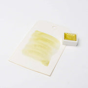 Muster gelber Aquarellfarbe auf weißer Karte neben einem kleinen quadratischen Tiegel mit Rico Design Farbe, der hoch konzentrierte Farbpigmente für beeindruckende Leuchtkraft zeigt.