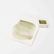 Ein Muster der schimmernden olivgrünen Aquarellfarbe Rico Design Metallic Aquarellfarben auf Papier neben einem kleinen Farbtopf.