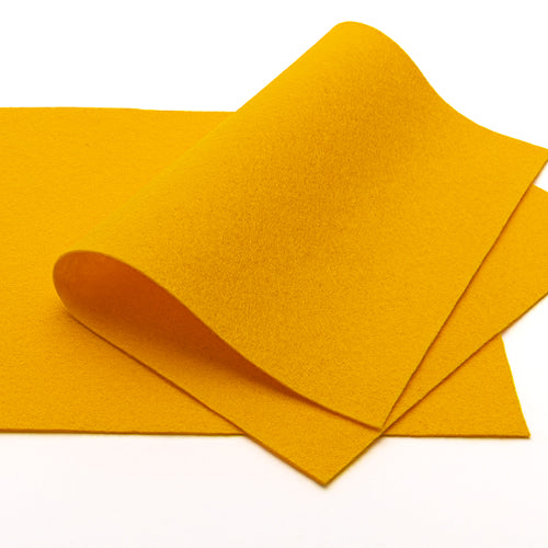 Zwei Blätter leuchtend gelber Filz von ☆, hergestellt aus weichem Merinowolle-Wollfilz, wobei ein Blatt teilweise gewellt auf dem anderen liegt, ruhen auf einer weißen Unterlage – perfekt als farbenfrohes Bastelmaterial für Ihre kreativen Projekte.
