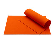 Zwei rechteckige Blätter aus leuchtend orangefarbenem ☆ Wollfilz, gefertigt aus weicher Merinowolle – ein Blatt liegt flach, das andere ist teilweise aufgerollt –, wodurch sie sich perfekt für Bastelarbeiten eignen.