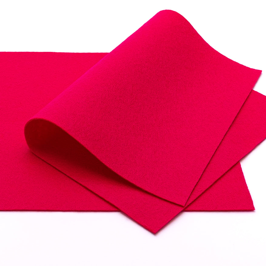 Zwei Bögen leuchtend pinkfarbener Wollfilz-Stoff von ☆, einer davon teilweise gefaltet, auf weißem Hintergrund – ideal für Bastelarbeiten und kreative Projekte.