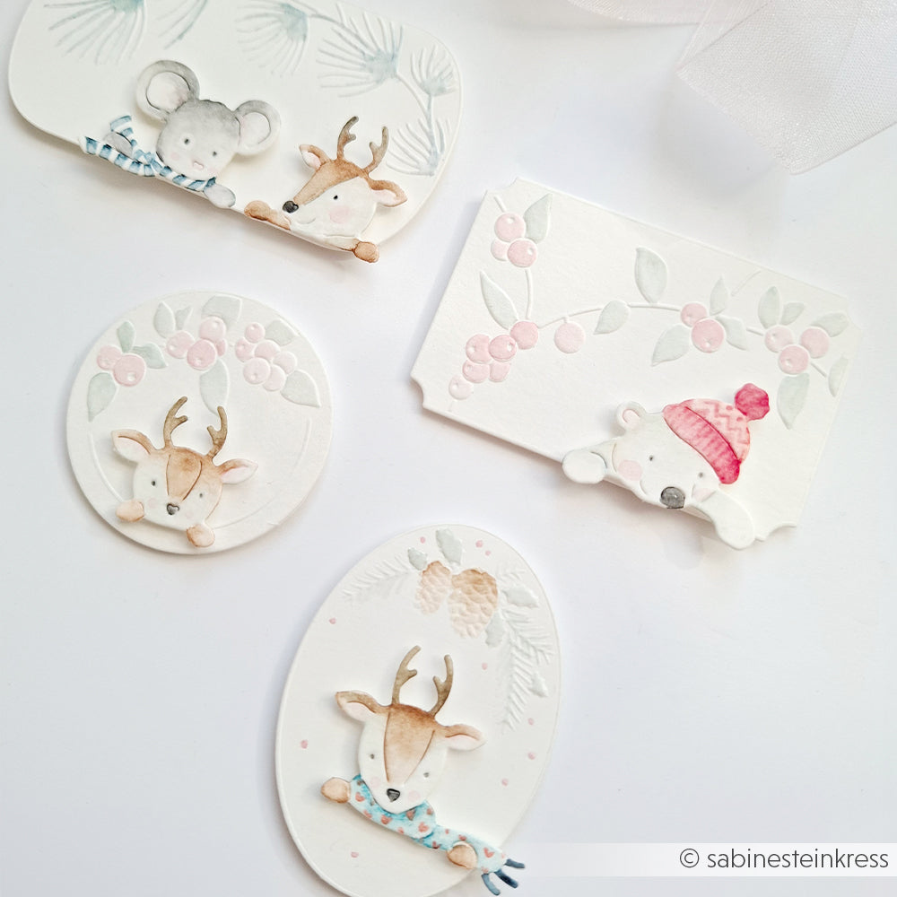 Vier weiße Kartenaufkleber mit Aquarellillustrationen einer Maus, eines Rehs und eines Bären in winterlicher Kleidung – ideal für die Verwendung mit einer Stanz- und Prägevorlage.