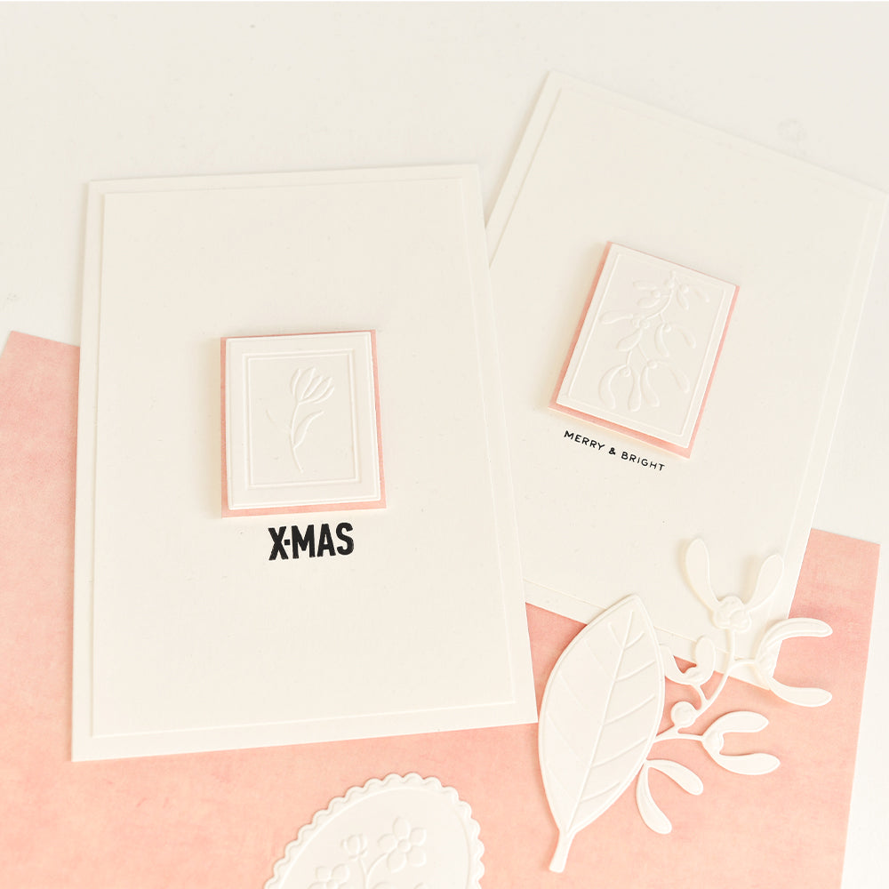 Zwei handgefertigte Weihnachtsgrußkarten mit geprägten Blumenmotiven, die mit einer Stanz- und Prägevorlage gestaltet wurden; auf der einen steht „X-MAS“, auf der anderen „MERRY & BRIGHT“.