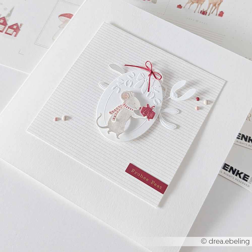 Handgefertigte Grußkarte mit einer Maus, die einen Schal trägt und ein Geschenk in der Hand hält; hergestellt mit Cut & Emboss-Prägefolien.
