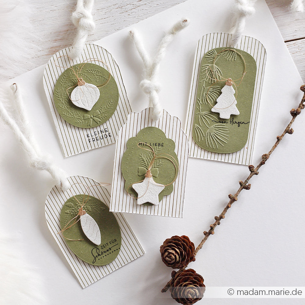 Vier handgefertigte Geschenkanhänger mit geprägten grünen Akzenten, Papierornamenten und deutschen Weihnachtsgrüßen, die mit Prägefolien mit Blumenmotiven gestaltet wurden.