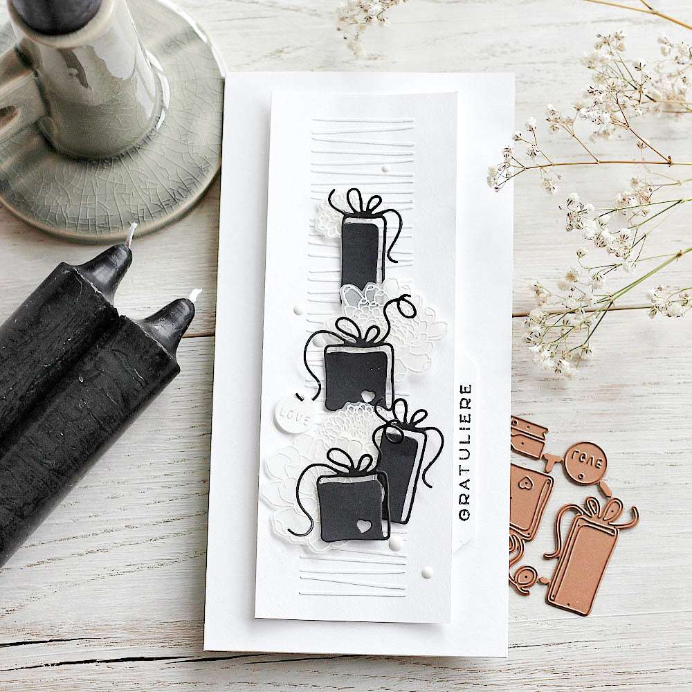 Handgemachte Grußkarte von Alexandra Renke mit drei schwarzen Geschenken aus Designpapier, hervorgehoben mit der Motivstanze Geschenkeset Paris, weißen Akzenten und dem Text "GRATULERE" daneben.