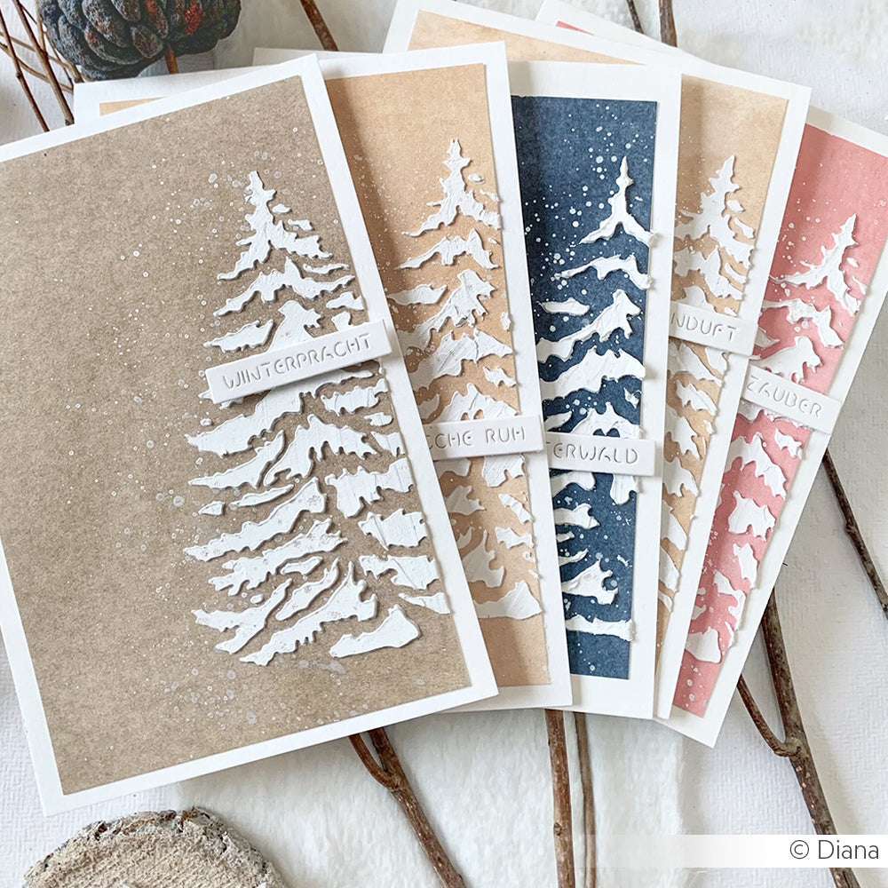 Die handgefertigten Winterkarten von Alexandra Renke zeigen strukturierte weiße Bäume, die mit der wiederverwendbaren Schablone Tannenbaum auf braunem, marineblauem und rosafarbenem Hintergrund erstellt wurden, akzentuiert mit deutschen Winterworten.