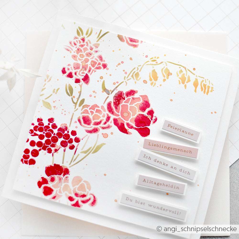 Quadratische Karte mit rosa-goldenem Blumenmuster und deutschem Text auf weißen Anhängern, hergestellt mit der wiederverwendbaren Blumenwirbel-Schablone von Alexandra Renke für elegante Schablonen-Effekte.