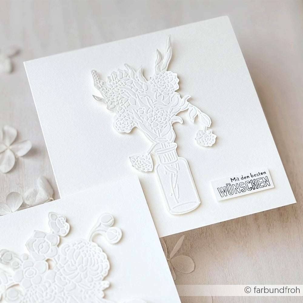Weiße Prägekarte von Alexandra Renke mit einer Blumenvase und dem deutschen Text "Mit den besten WÜNSCHEN". Zeigt das Stencil Dahlienstrauß Design, ideal zum Basteln mit wiederverwendbaren Schablonen.