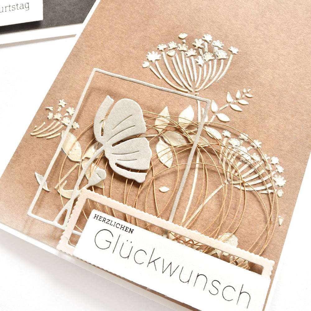 Handgefertigte Karte von Alexandra Renke mit weißen Blumen- und Schmetterlingsmotiven, goldenen Drahtakzenten und dem Text "Herzlichen Glückwunsch", hergestellt mit wiederverwendbaren Schablonen für einzigartige Schablonen Papierprojekte.