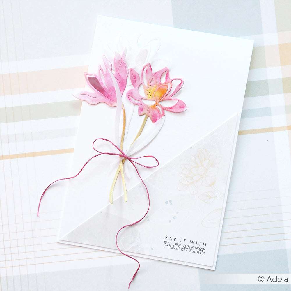 Eine handgefertigte Karte von Alexandra Renke mit rosa Aquarellblumen, hergestellt mit Motivstanze Blumenpaar und Designpapieren, verziert mit einer Schleife und dem Text "Say it with FLOWERS" auf weißem Hintergrund.
