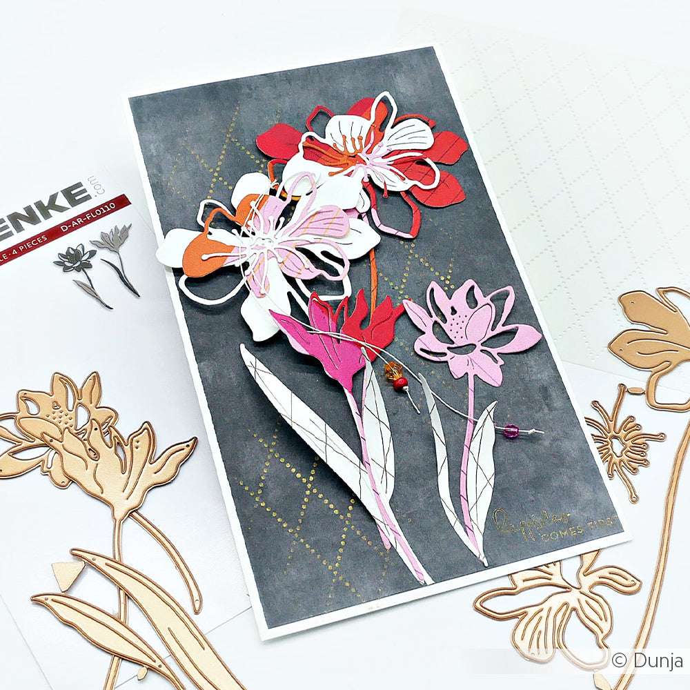 Handgemachte Karte mit geschichteten rosa, roten und weißen Papierblumen, die mit der Motivstanze Blumenpaar von Alexandra Renke auf einem dunklen Hintergrund hergestellt wurden, umgeben von Bastelmaterial.