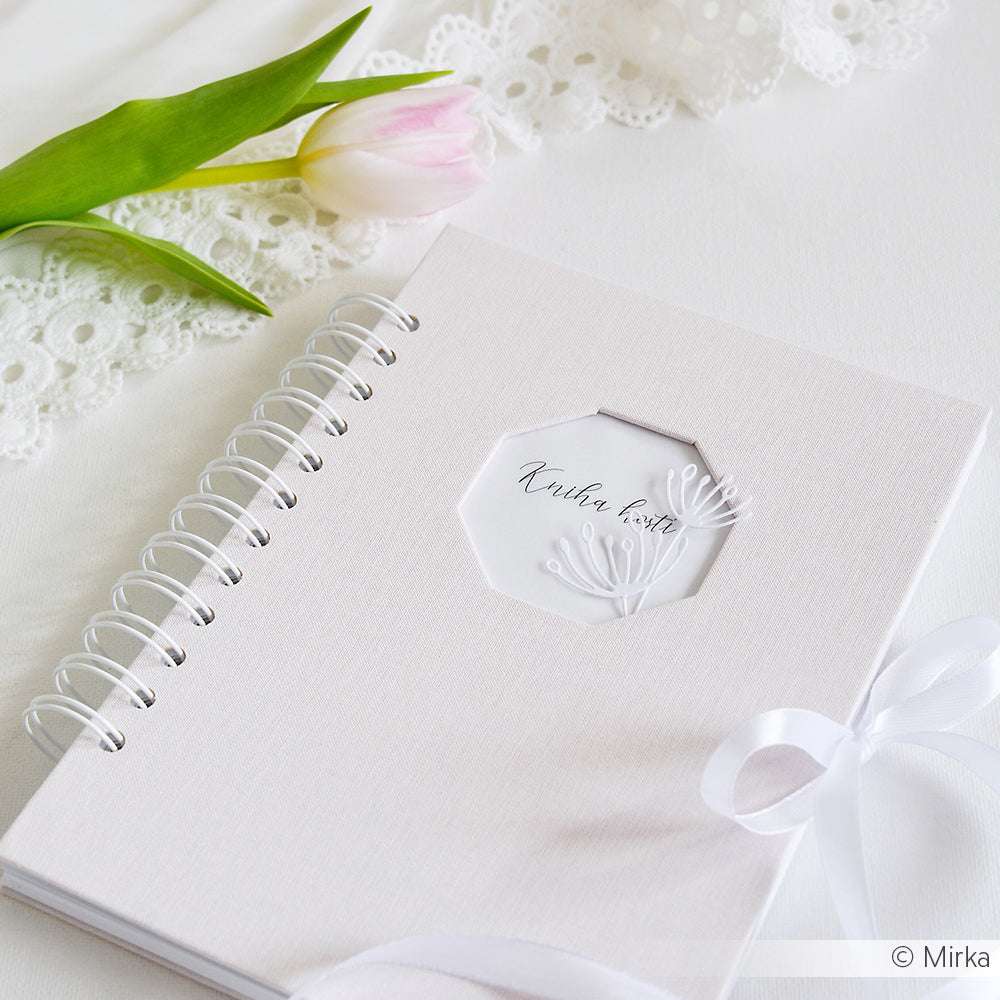 Ein weißes, spiralgebundenes Notizbuch mit einem Lesebändchen liegt auf einer weißen Fläche neben einem Spitzentuch, einer rosa Tulpe und dekorativen Alexandra Renke Artistblumen Set Dies.