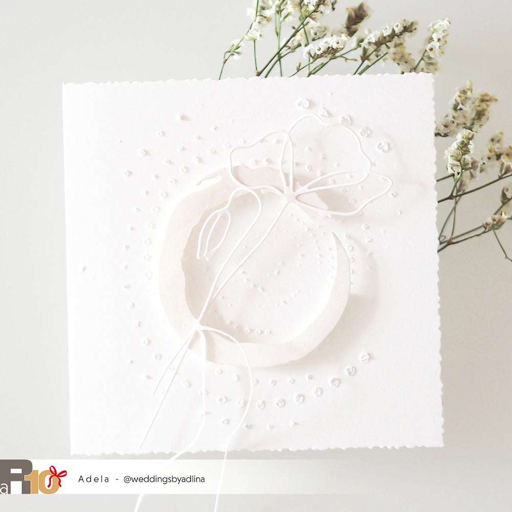 Zarte weiße Prägekarte mit floralem Muster, gestaltet mit Alexandra Renke Motivstanze Artistblumen und feinen Designpapieren, akzentuiert durch kleine weiße Blüten im Hintergrund.