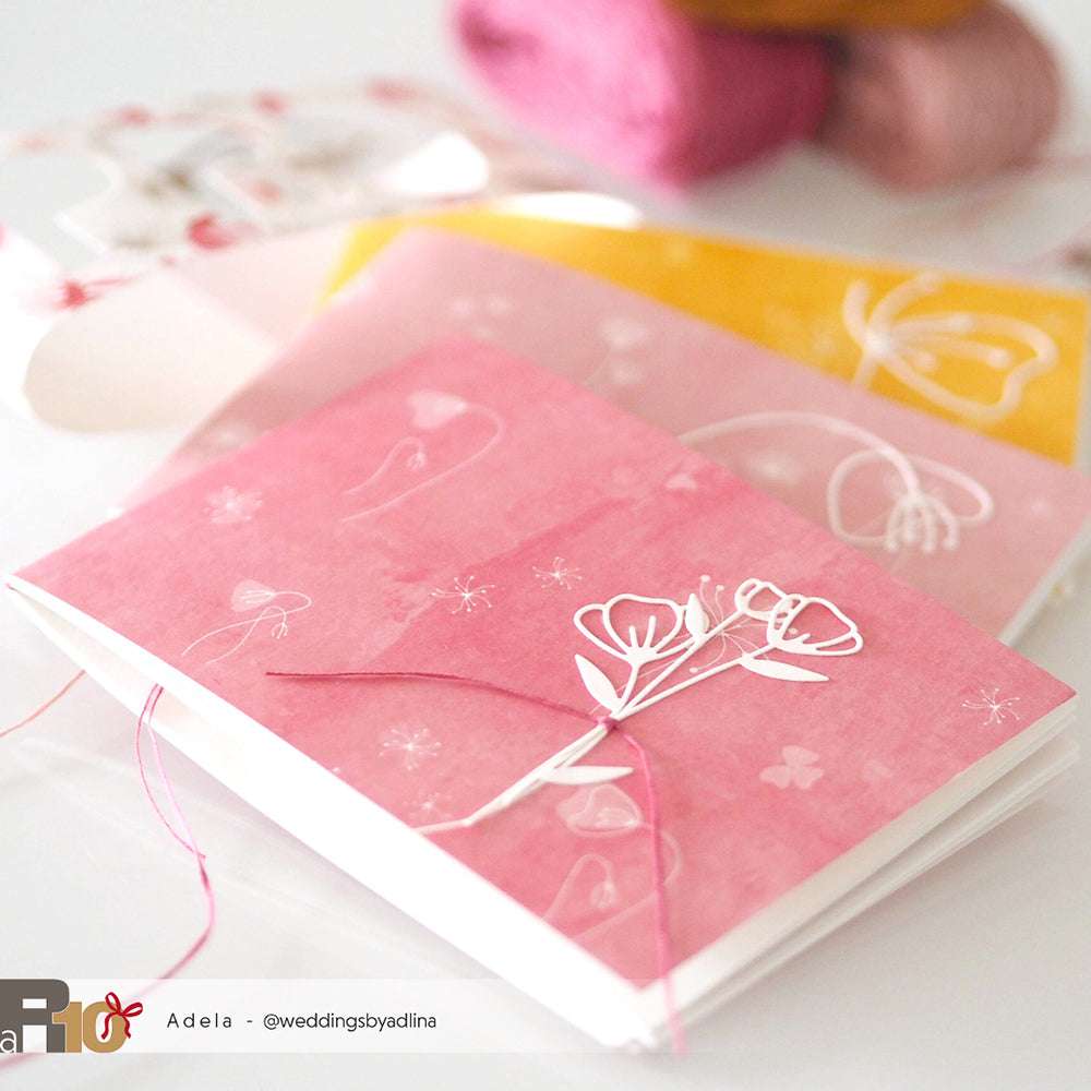 Rosa, gelbe und weiße handgefertigte Grußkarten mit floralen Motiven - gestaltet mit Alexandra Renke Motivstanze Artistblumen - liegen teilweise geöffnet auf einer weißen Fläche.