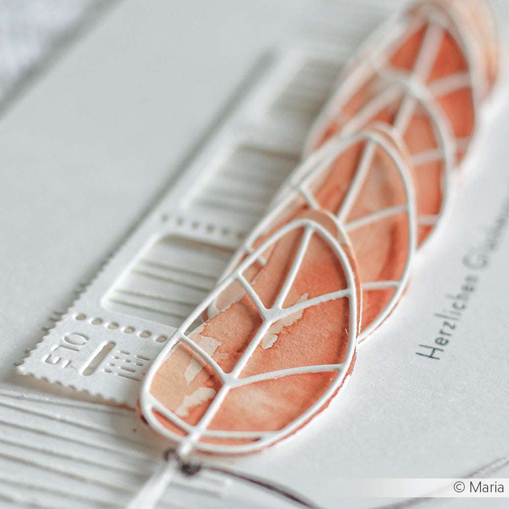 Nahaufnahme einer handgefertigten Karte mit orangefarbenen Aquarellblättern, einem weißen gestanzten geometrischen Muster, hergestellt mit Alexandra Renke Artist Blatt 3 Stanzsysteme auf hochwertigem Designpapier.