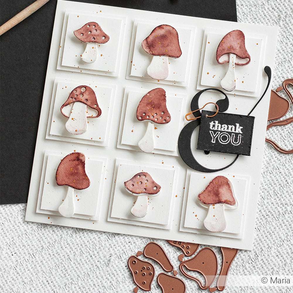 Handgefertigte Danksagungskarte mit neun roten Pilzen, die mit den Alexandra Renke Artist Pilz 4 Stanzformen auf weißen Quadraten arrangiert und mit einem schwarzen "Danke"-Anhänger versehen wurden.