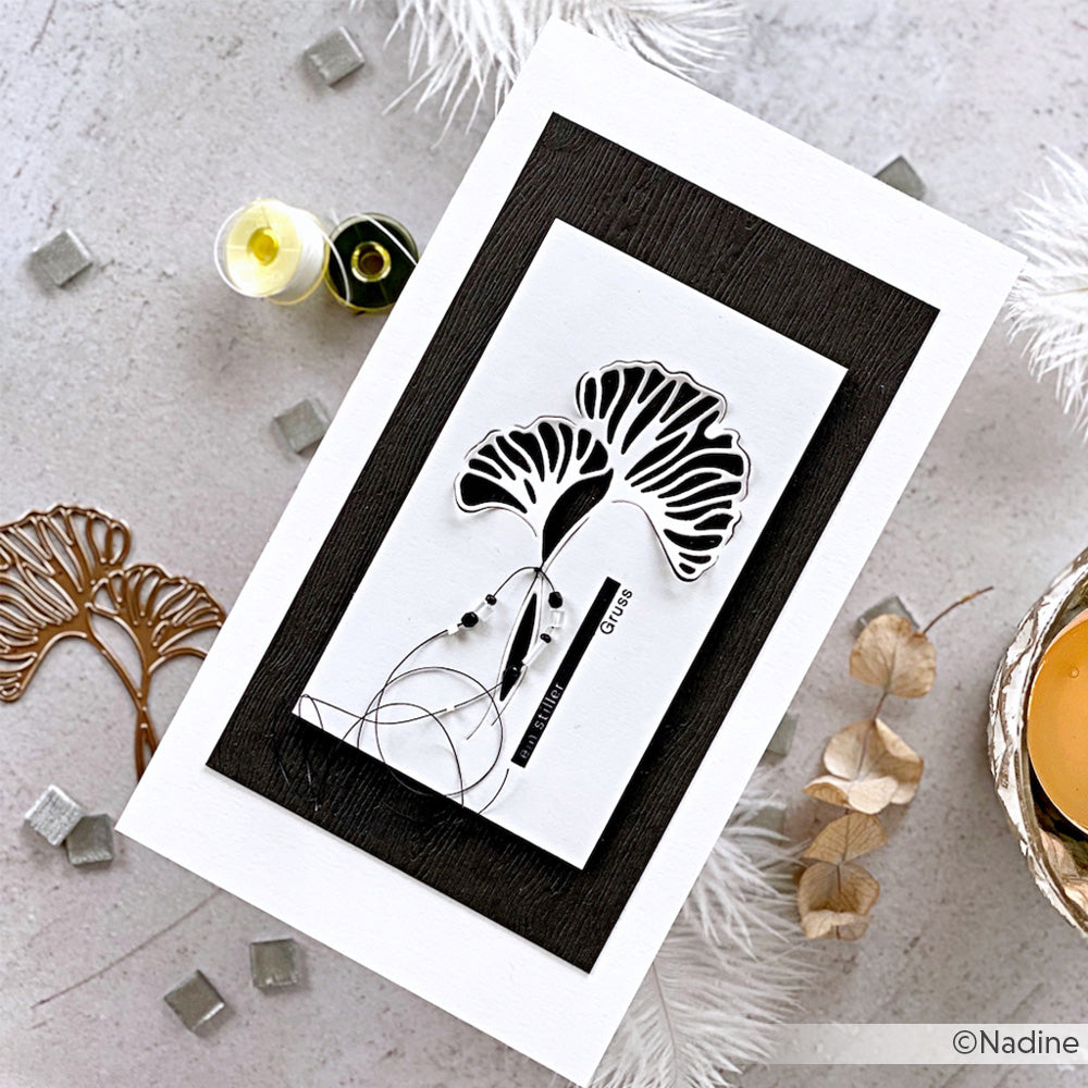 Moderne schwarz-weiße Grußkarte von Alexandra Renke mit einem abstrakten Baummotiv, hergestellt mit hochwertigen Designpapieren und DieCut Systemen, inmitten von Getränken und Dekorationsartikeln.