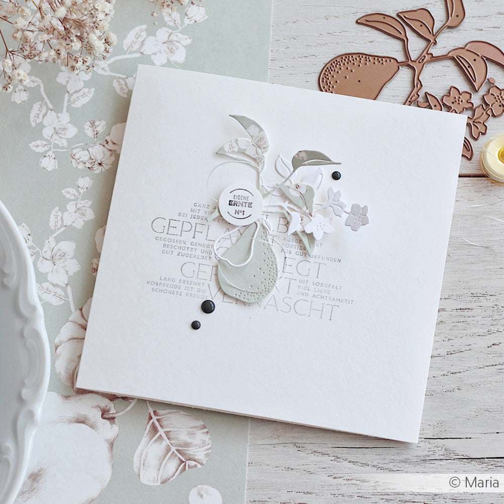 Elegante, handgefertigte Karte von Alexandra Renke aus hochwertigem Designpapier mit weißen und grauen Blüten und Blättern, die mit der Motivstanze Birnenzweig Duo auf einem hellen, strukturierten Hintergrund gestaltet wurden.