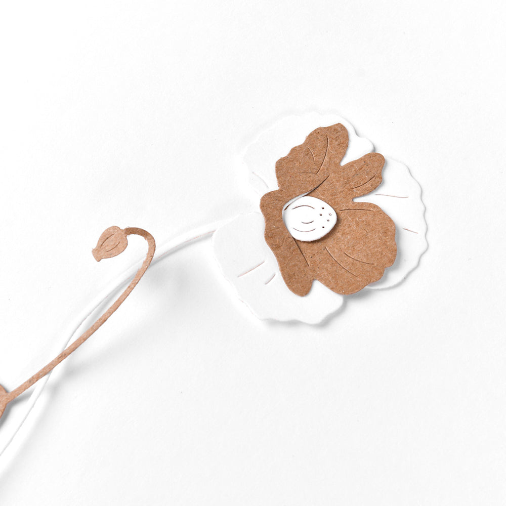 Scherenschnittblume mit den Stanzformen Schichtblume 6 von Alexandra Renke, mit weißen und braunen Blütenblättern und einem gebogenen Stiel auf weißem Hintergrund.