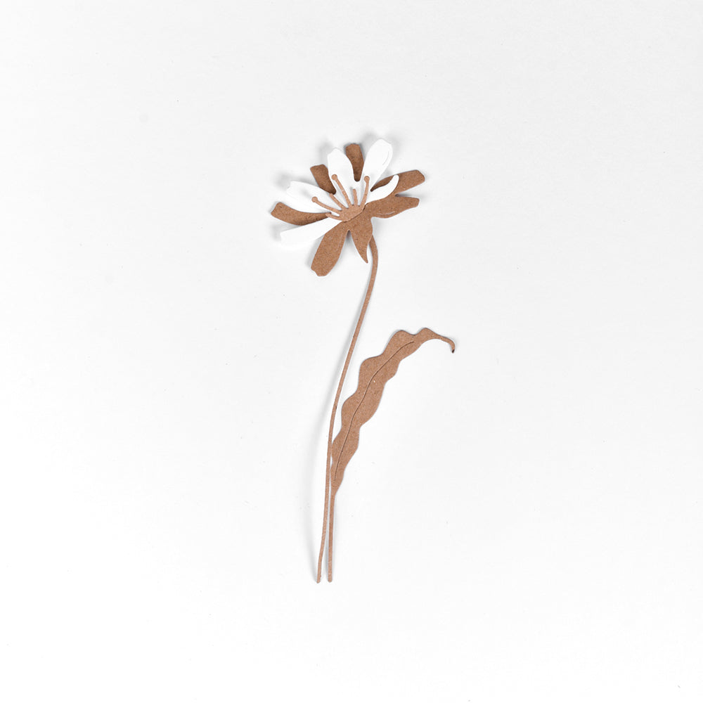 Eine schlichte braune Papierblume mit einem einzelnen Blatt, hergestellt aus hochwertigen Designpapieren unter Verwendung der Motivstanze Schichtblume 8 von Alexandra Renke, auf einem schlichten weißen Hintergrund.