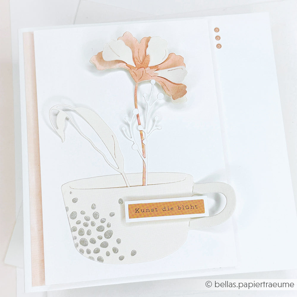 Handgefertigte Karte von Alexandra Renke mit einer Teetasse und einer Irisblüte aus Schichtblume 10 und Motivstanze, deutschem Label "Kunst die blüht" und eleganten Designpapieren auf weißem Hintergrund.