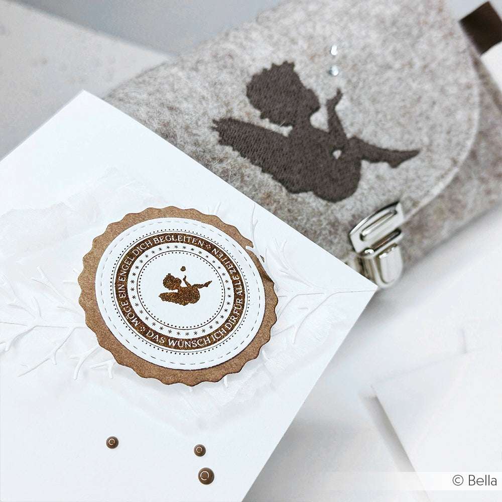 Weiße Grußkarte mit braunem Engelssiegel neben einem grauen Filzbeutel mit Engelssilhouette, perfekt zur Kombination mit Alexandra Renke Designpapieren oder zur Verwendung mit Stanzsystemen wie der Motivstanze Zypressenzweig.