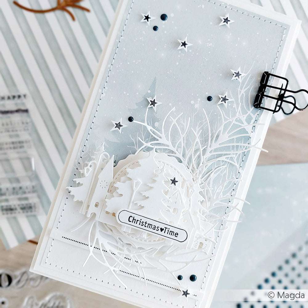 Handgemachte Karte mit einer verschneiten Winterlandschaft und Bäumen, ausgestanzt mit Alexandra Renke Dies und Motivstanze Kleines Tannen-Duo 2, verziert mit Sternen und einem Weihnachtszeit-Etikett auf der Vorderseite.