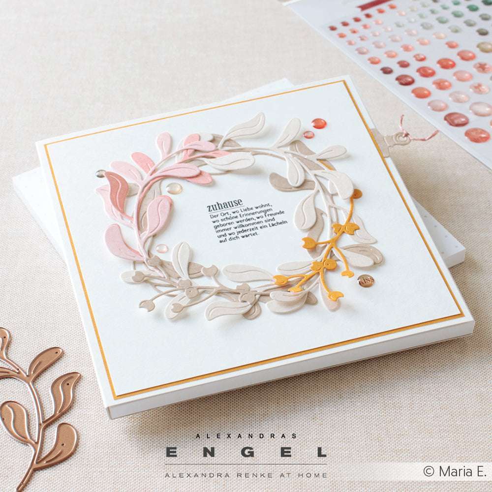 Quadratische Grußkarte von Alexandra Renke mit einem geschichteten Papierkranz in Rosa, Beige und Gold auf Weiß, hergestellt mit Dies und der Motivstanze Steck-Mistelzweig für detaillierte Akzente.