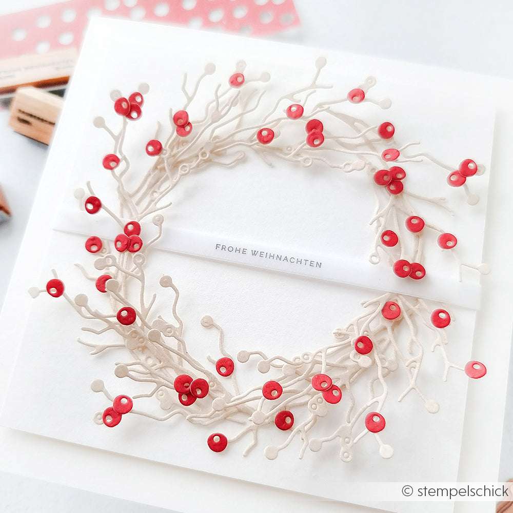 Eine handgefertigte Weihnachtskarte von Alexandra Renke, die einen Beerenkranz mit Vögeln, einen weißen Kranz, rote Beeren, eine Motivstanze und den Text "Frohe Weihnachten" zeigt.
