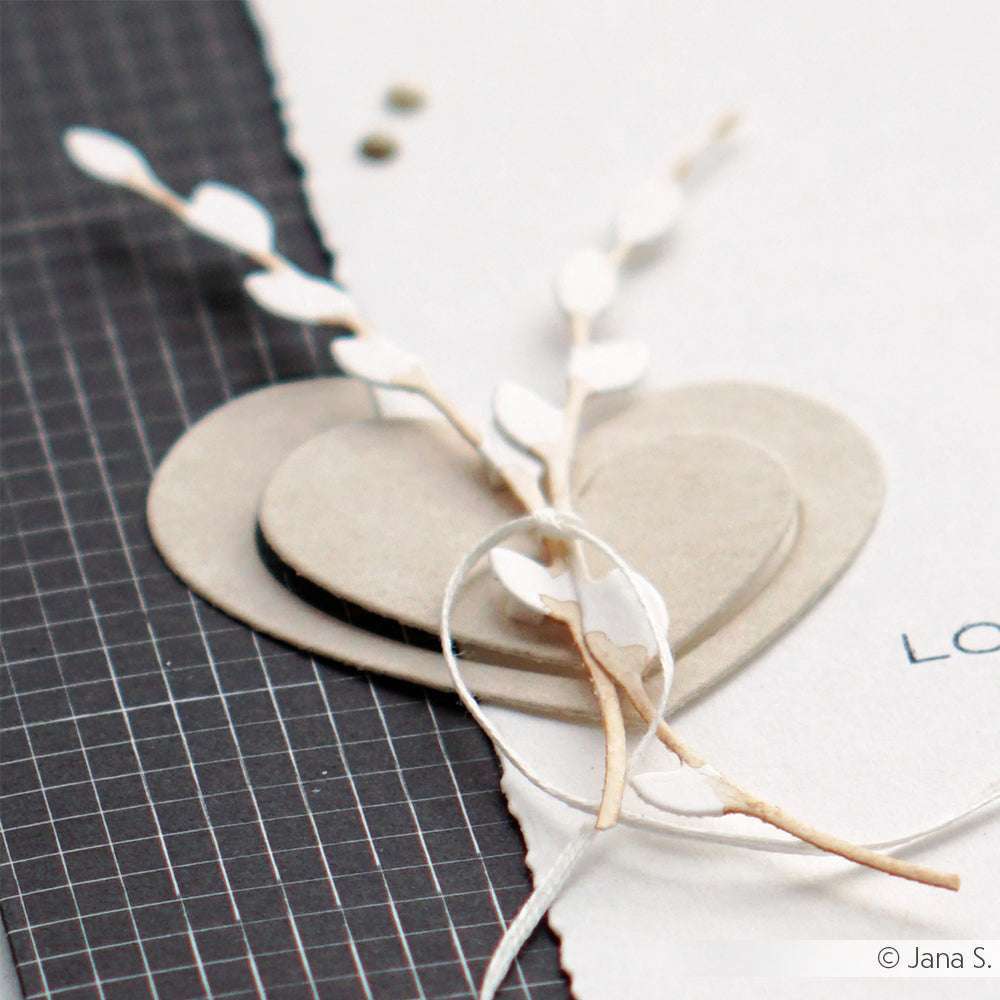 Zwei geschichtete Papierherzen, Zweige aus Alexandra Renke Designpapieren und Schnur auf einem strukturierten Gitter und einfarbigem Hintergrund - perfekt, um die Alexandra Renke Motivstanze Weidenkätzchenkranz in Szene zu setzen.