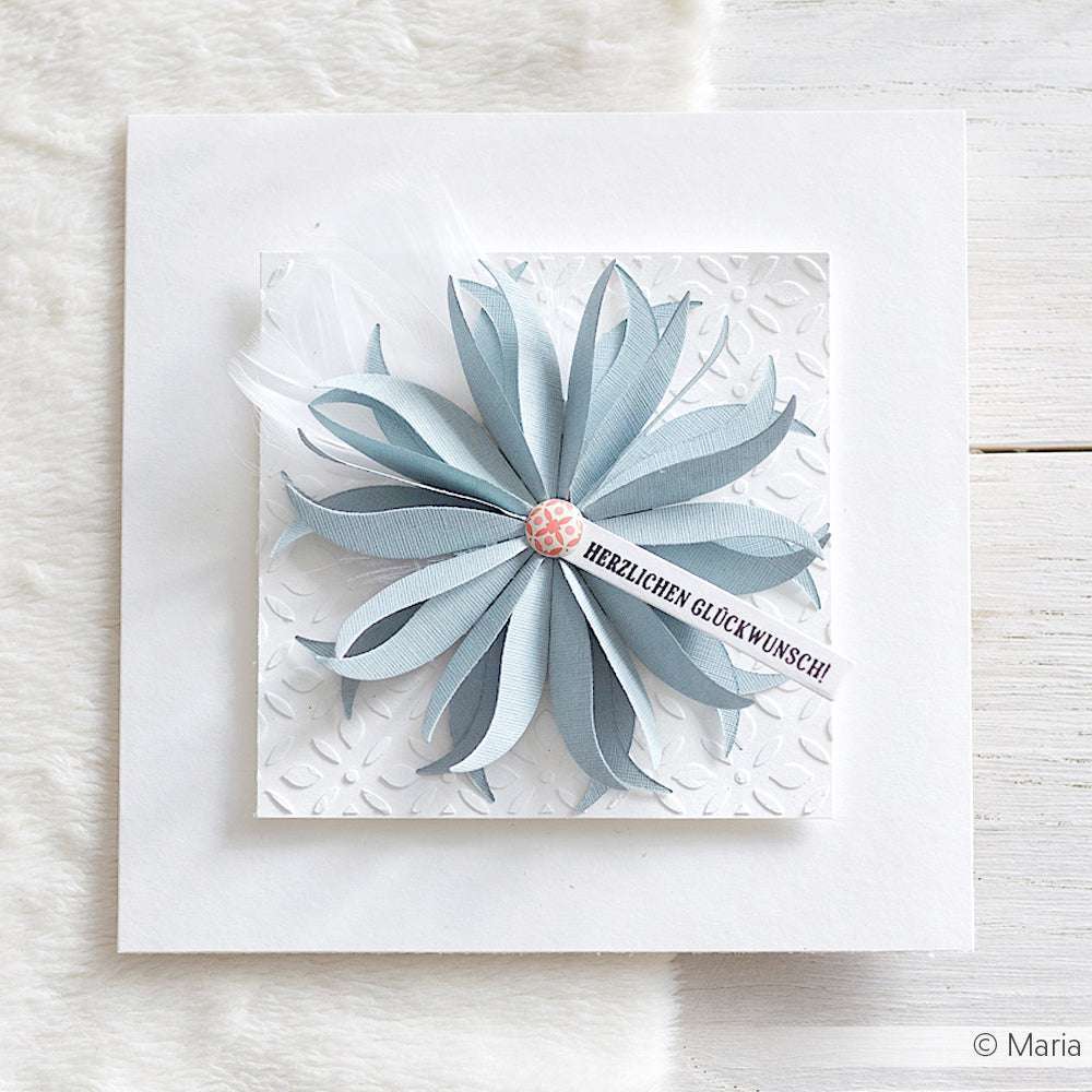 Quadratische Karte mit einer großen blauen Papierblume aus Motivstanze Faltblume, einer Feder und einem "Herzlichen Glückwunsch!"-Banner auf strukturierten Premium Designpapieren von Alexandra Renke.