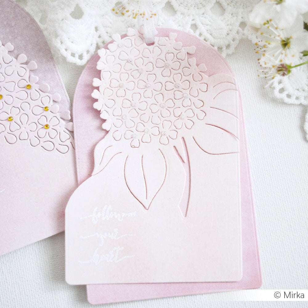 Pastellrosafarbene Blumenkarte von Alexandra Renke aus Designpapier und einer Negativ-Blume mit gestanztem Motiv, das einen filigranen Blumenausschnitt und einen eleganten kursiven Text auf weißem Hintergrund mit Spitze zeigt.