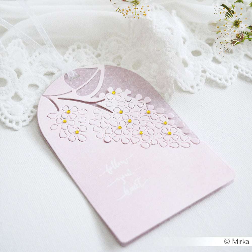 Zartrosa Blumenanhänger mit geprägten Blumen, gelber Mitte und weißer Spitze im Hintergrund - hergestellt mit Alexandra Renke's DieCut Systemen und Motivstanze Negativ-Blume 2 für einen zarten Touch.