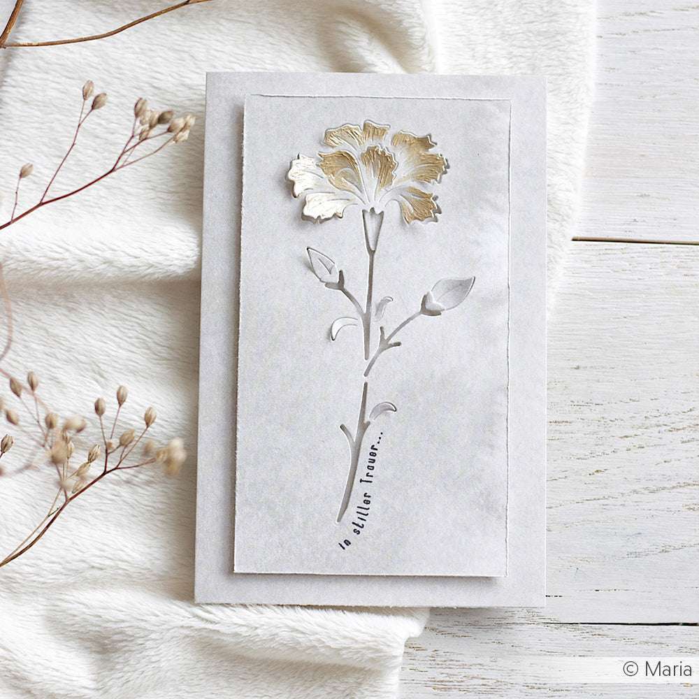 Eine handgefertigte Karte von Alexandra Renke aus Designerpapier zeigt eine ausgeschnittene Blume (Motivstanze Negativ-Blume) und den Schriftzug "in erwachsenen Stunden" auf dem Stängel, dargestellt auf einer weißen Fläche.