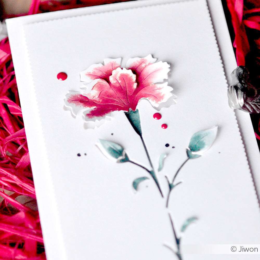 Eine handgefertigte Karte von Alexandra Renke zeigt eine gemalte rosa Blume mit grünen Blättern auf weißem Papier, akzentuiert durch rosa Ziergras, hergestellt mit Designpapier und detailliert mit der Motivstanze Negativ-Blume 6.