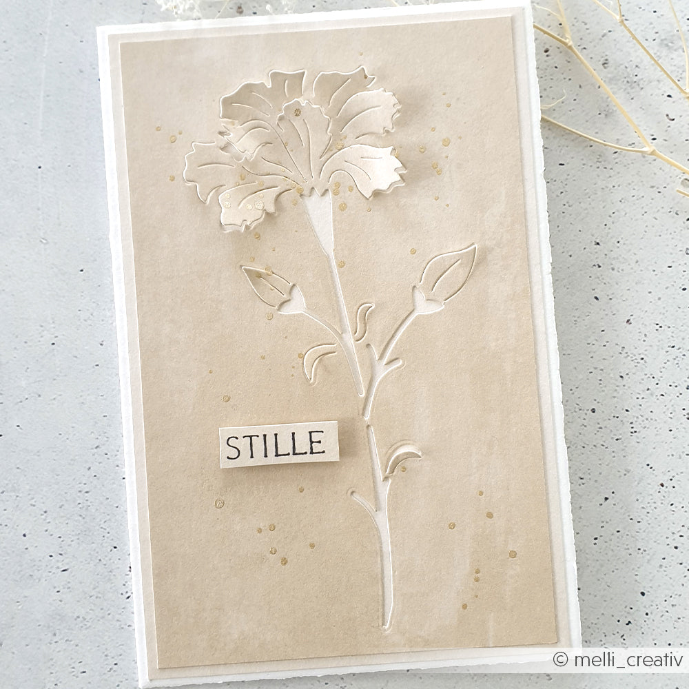 Handgefertigte Karte von Alexandra Renke mit einer beigefarbenen, mit Motivstanze Negativ-Blume 6 geprägten Blume und dem Wort "STILLE" auf der Vorderseite, vor einem neutralen Hintergrund.