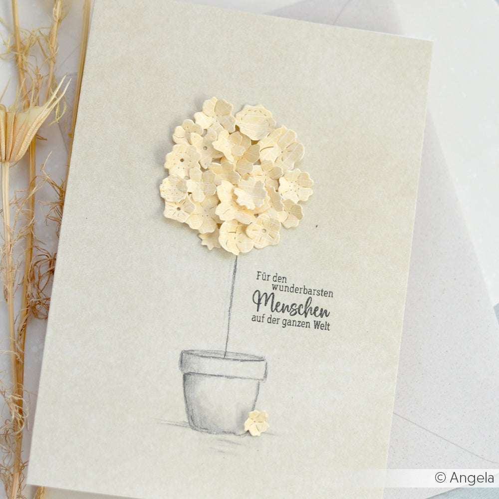 Handgemachte Karte mit einer Blume in einem Topf mit deutschem Text, verziert mit cremefarbenen Papierblumen. Hergestellt mit Alexandra Renke Motivstanze Blumenwiese Stanzen für Designpapier für zusätzliche Details und Charme.