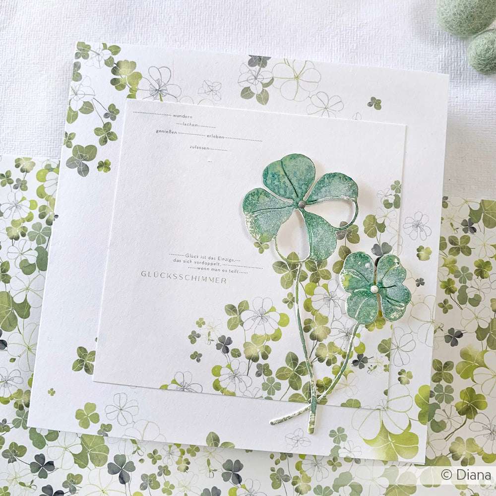 Eine Karte mit grünen Aquarellkleeblättern auf Weiß, wunderschön verziert mit Kleemustern - perfekt, um Ihre Motivstanze Glücksklee Duo zu präsentieren oder mit den passenden Designpapieren von Alexandra Renke zu kombinieren.