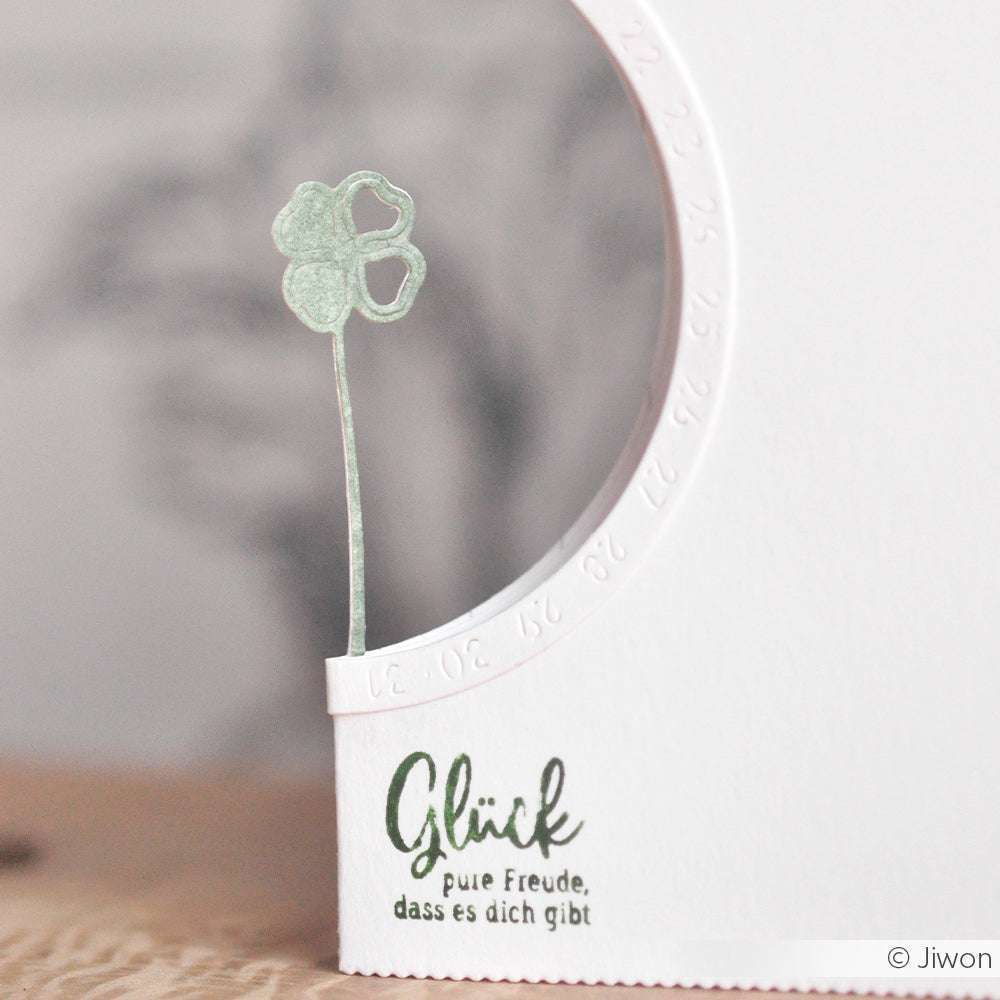 Minimalistische Karte von Alexandra Renke mit einem grünen vierblättrigen Kleeblatt, einem geschwungenen Kalender und einem deutschen Text: Glück, pure Freude, dass es dich gibt. Gestaltet mit der Glücksklee-Motivstanze und hochwertigen Stanzformen von modern systems.