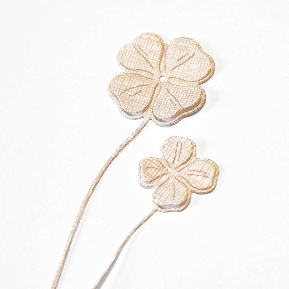 Zwei metallische vierblättrige Kleeblätter mit strukturierter Oberfläche unterstreichen die gestalterische Eleganz von Alexandra Renke und die Präzision der Motivstanze Glücksklee Duo DieCut Systeme auf weißem Hintergrund.