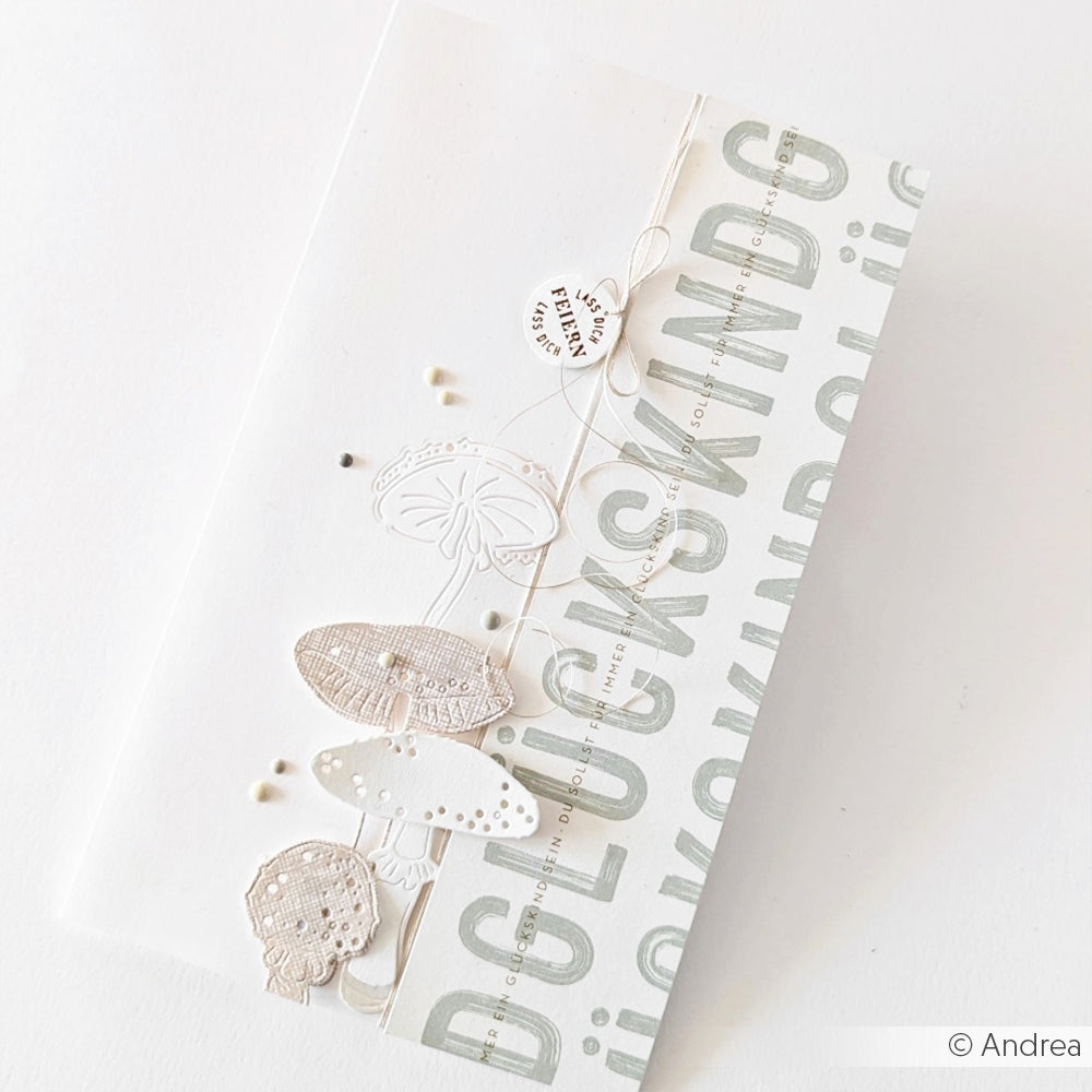 Minimalistische Karte von Alexandra Renke mit neutralen Pilzen und Schnur, mit "GLÜCKS KIND" auf einem hellgrauen Streifen - gestaltet mit Designpapieren und Motivstanze Glückspilz Duo für einen modernen, stilvollen Look.