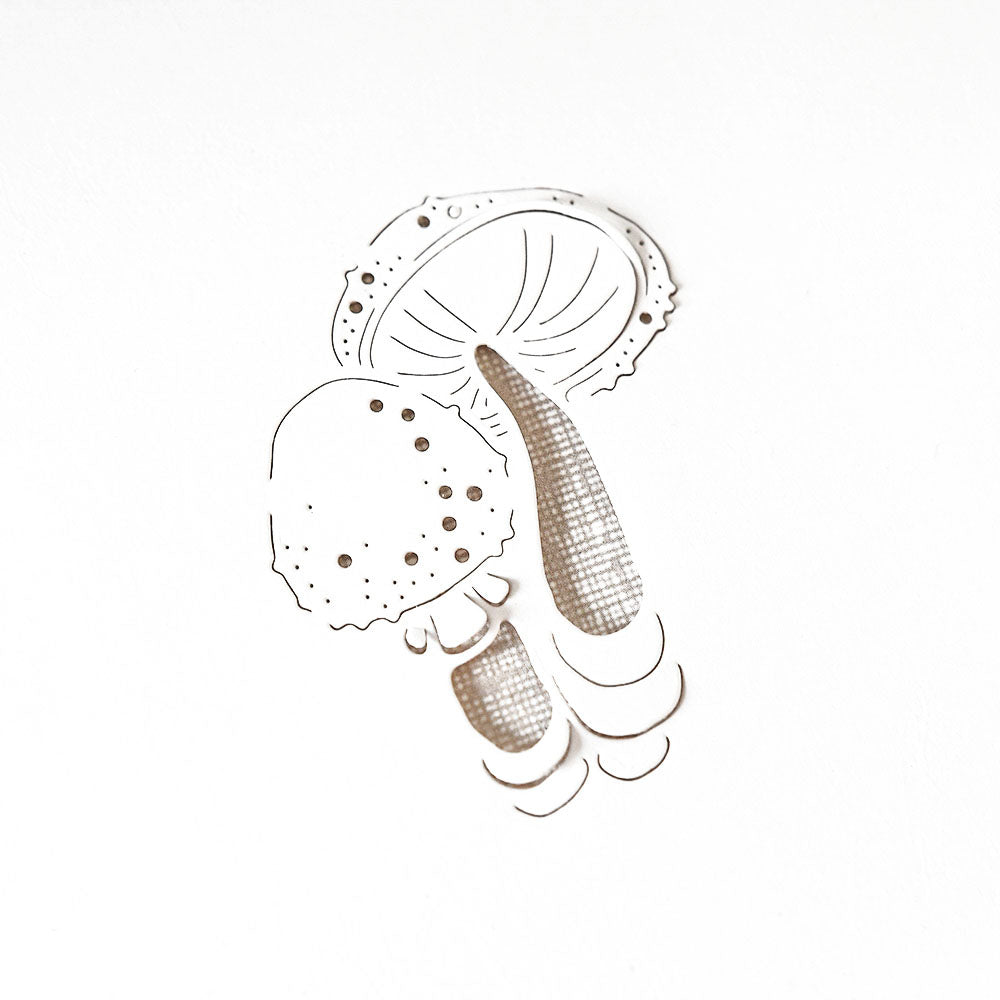 Minimalistische Illustration und Scherenschnitt eines Pilzes mit schwarzen Tuschedetails auf Weiß, hergestellt mit der Alexandra Renke Motivstanze Glückspilz für scharfe Kanten und klare Linien.