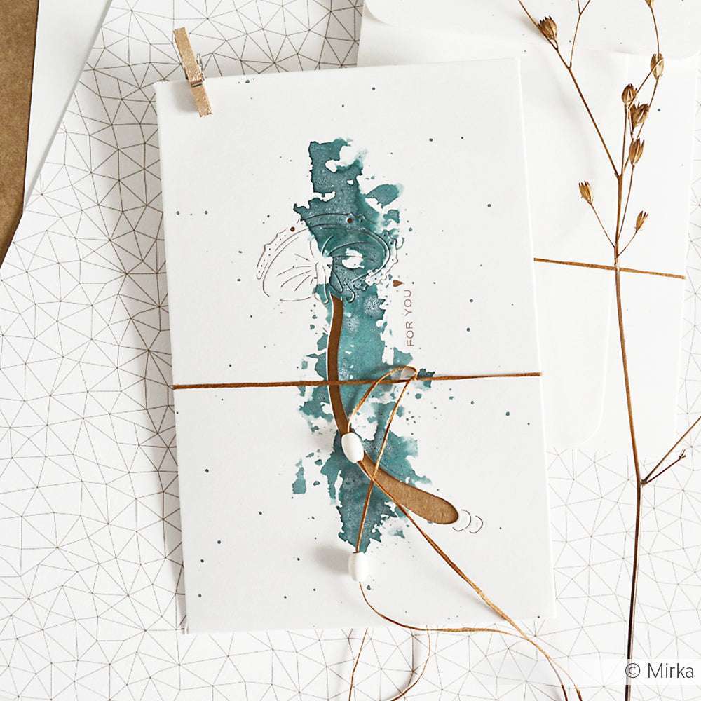 Künstlerische Karte von Alexandra Renke mit Aquarellfarben in Grüntönen, Bindfäden und getrockneten Pflanzen, hergestellt mit den Stanzsätzen Stanzsysteme und Motivstanze Glückspilz Negativ 2, auf geometrisch gemustertem Papier.