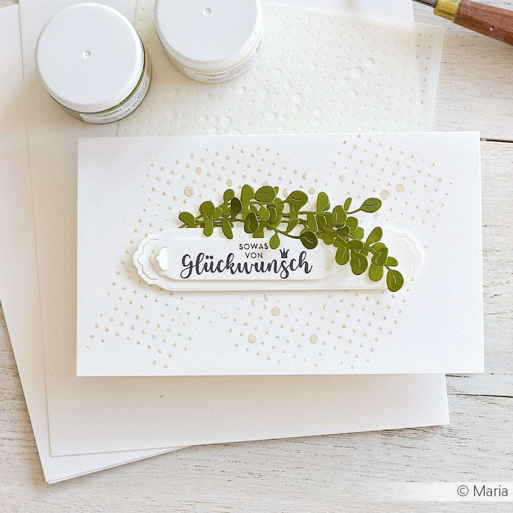 Eine handgefertigte Karte von Alexandra Renke mit Designpapieren und grünen Eukalyptusblättern (Motivstanze Eukalyptus Trio) mit deutschem Text und gepunkteten Mustern, wunderschön auf einem weißen Tisch präsentiert.