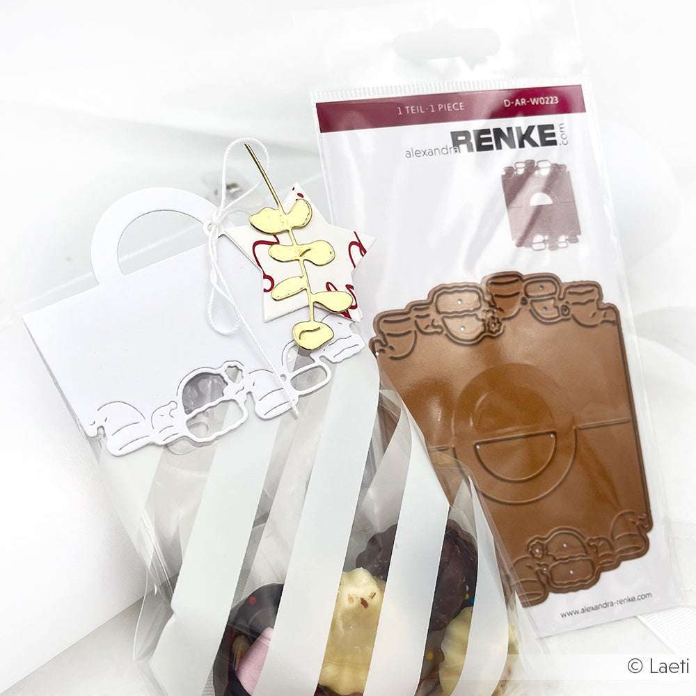 Geschenktüte mit gestreifter Verpackung, weißem Henkel, Wolkendekoration und einer Alexandra Renke DieCut Systeme Motivstanze Eukalyptus Trio im Hintergrund.